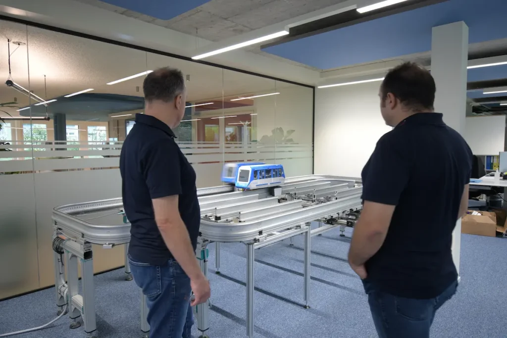 Zwei Inautec-Ingenieure überwachen die Simulation eines fahrerlosen Monorail-Modells auf dem Prüfstand zur Validierung von Sicherheitsfunktionen in Wollerau, Schweiz.